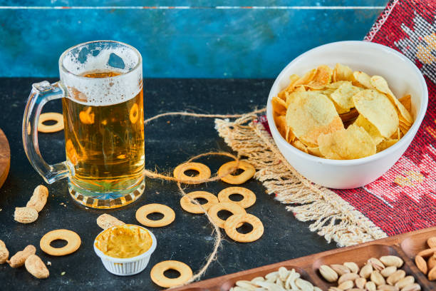 istock Assorted snacks, chips and a glass of beer on dark table 1298612726