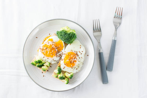 Bruschetta with scrambled eggs and broccoli on a grain crispbread with sesame seeds and flaxseed on a plate on the table. Top view