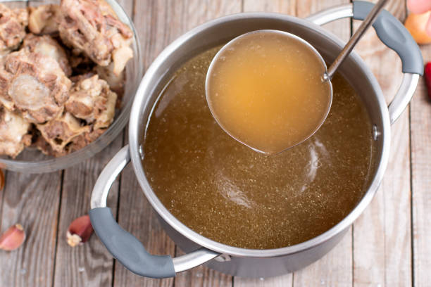 istock Saucepan with bouillon with a ladle on a wooden table. Bone broth 1298613972