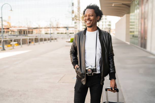 istock Tourist man carrying suitcase while walking outdoors. 1298617350
