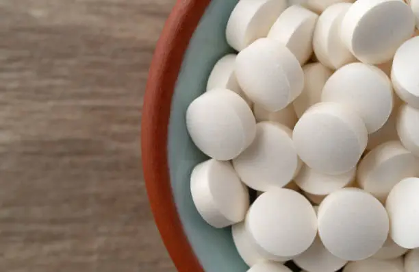 Photo of DHEA pills in a bowl on a table top close view