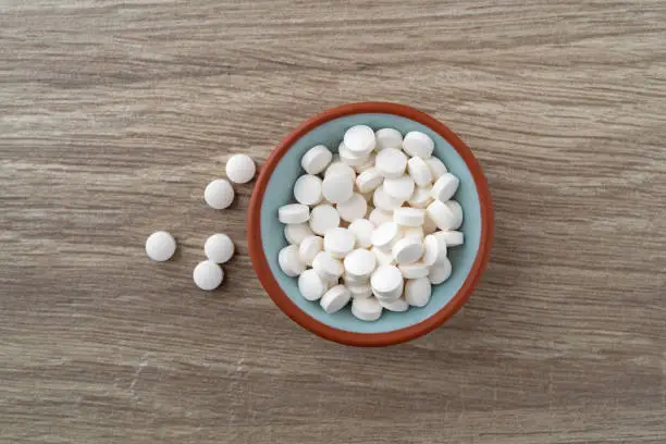 Photo of DHEA pills in a bowl on a table top view