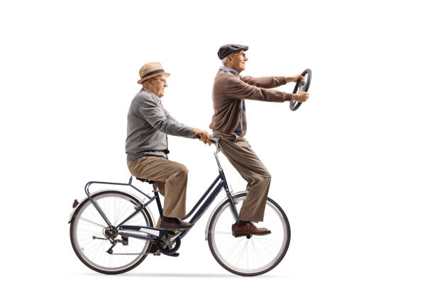 istock Two elderly men riding on a bicycle and holding a steering wheel isolated on white background 1298620625