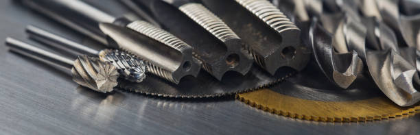 set of different drill bits,thread tap and mill cutters with caliper ruler on steel plate background. Locksmithing deal.