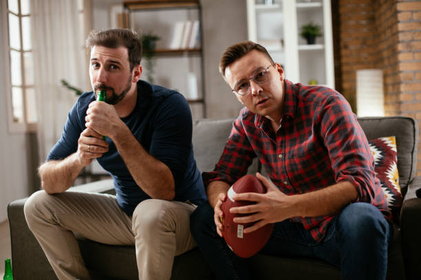istock Men drinking beer and watching sports game on tv. 1298621679