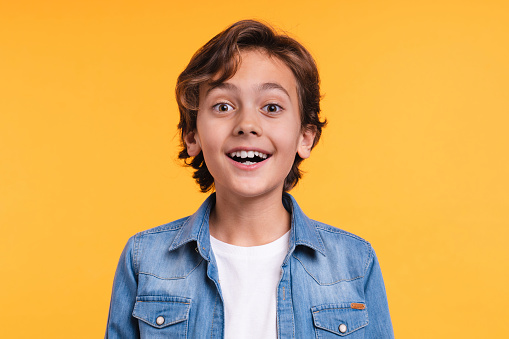 Close up portrait of 10s small surprised boy in casual clothes isolated over yellow background