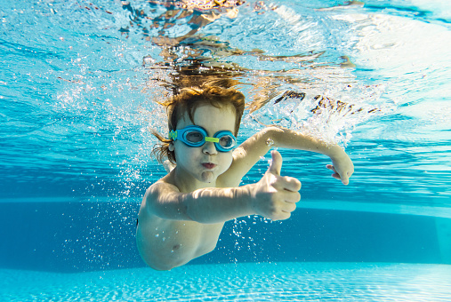 Front view of boy whit thumb up diving underwater