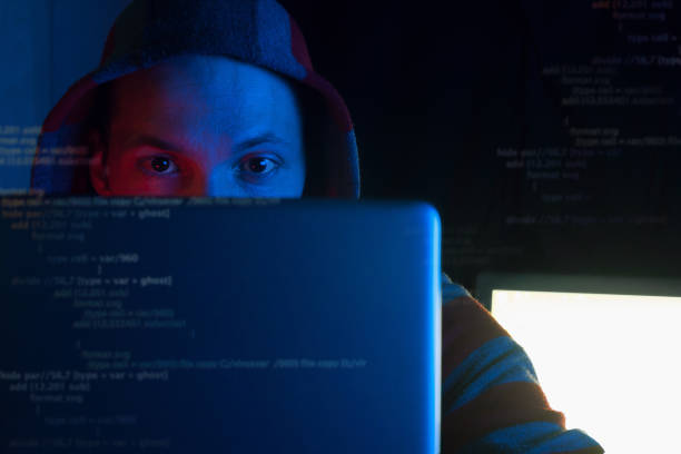 istock anonymous programmer, hacker in hoodie coding on laptop in dark room in red blue neon light, front view hacker gaze into  monitor and program code in screen, cyber security and hacking attack concept 1298623010