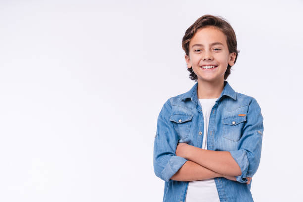 Happy young caucasian boy in casual outfit with arms crossed isolated over white background stock photo