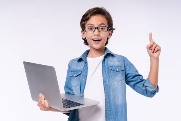 istock Smart small male kid having idea with laptop isolated over white background 1298623252