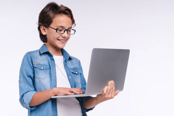 istock Smiling happy little boy using laptop isolated over white background 1298623254