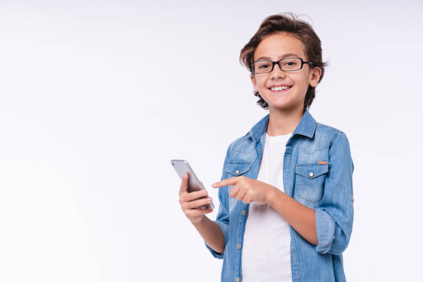 Happy little child pointing at smart phone isolated over white background
