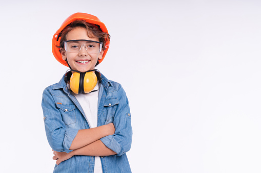 Smiling young future construction worker in uniform isolated over white background