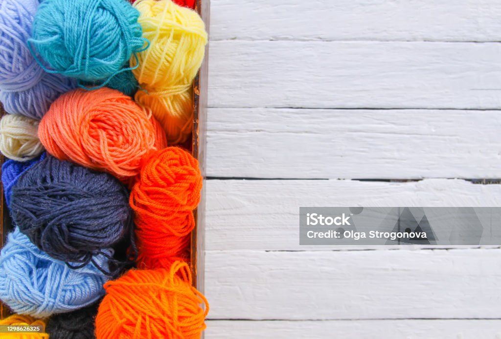 Colorful yarn balls in wooden box on white wood boards background. Ball Of Wool Stock Photo