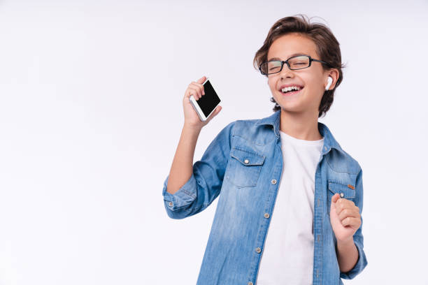 little male kid enjoying music on his phone uing headphones isolated over white background - child little boys male caucasian imagens e fotografias de stock