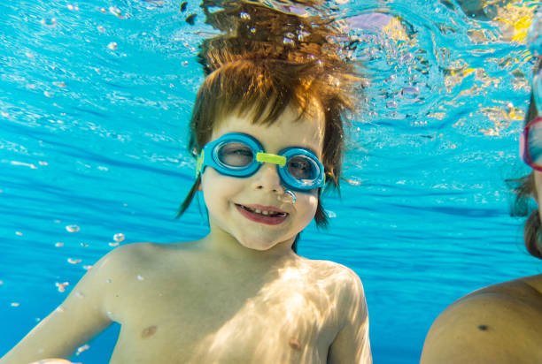 istock Little boy whit swimming goggles diving into water 1298626604
