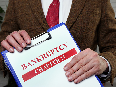 Documents about bankruptcy chapter 11. Man holds papers.