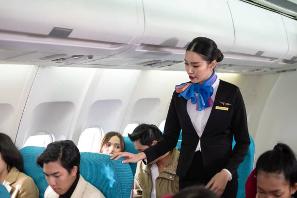 istock Stewardess in uniform looking all passengers to fasten seat belt while sitting on the airplane for safety flight. The security system is rigorous. Checking passenger before take off. Security concept 1298634981