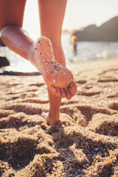 Cropped shot of an unrecognizable woman walking in the sand