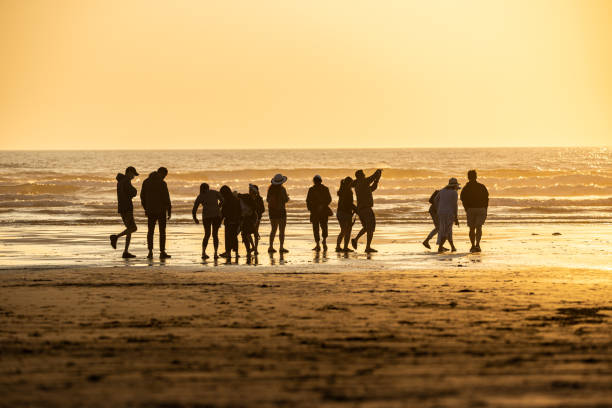 istock Silhouetted group of people gathered on a beach at sunset 1298636067