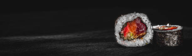 istock sushi roll with fish and rice on black wooden table background 1298637425