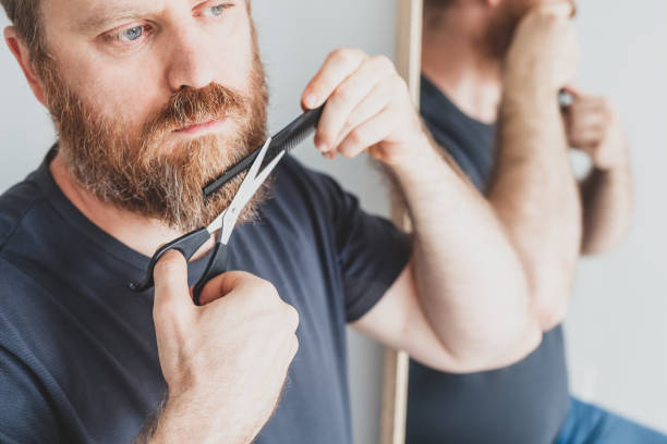istock Man cutting moustache and beard himself at home 1298639413
