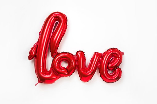 Red golden word LOVE made of inflatable balloons isolated on white background. Red foil balloon letters, concept of romance, Valentine's Day, Mothers Womans Day