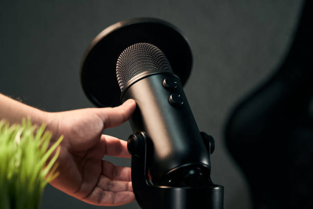 istock hand of a man about to take a black microphone on a dark gray background 1298641652