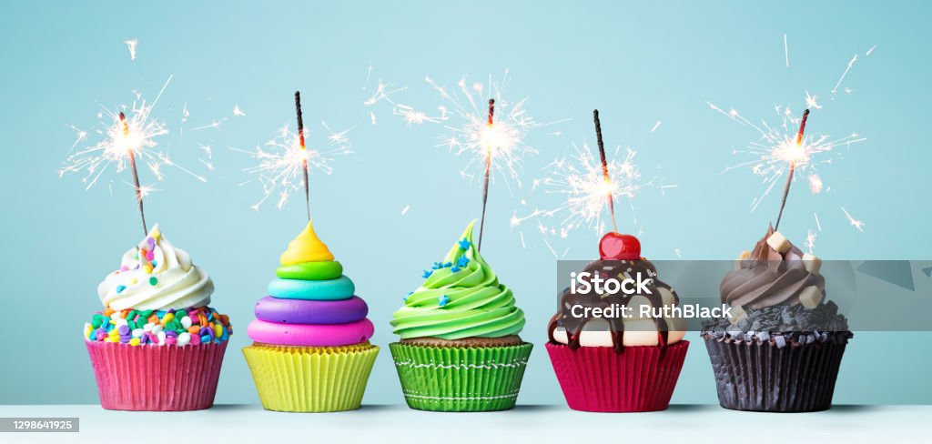 Colorful celebration cupcakes Assortment of brightly colored celebration cupcakes decorated with sparklers for a birthday party Birthday Stock Photo