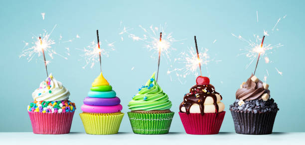 Colorful celebration cupcakes Assortment of brightly colored celebration cupcakes decorated with sparklers for a birthday party dessert topping photos stock pictures, royalty-free photos & images