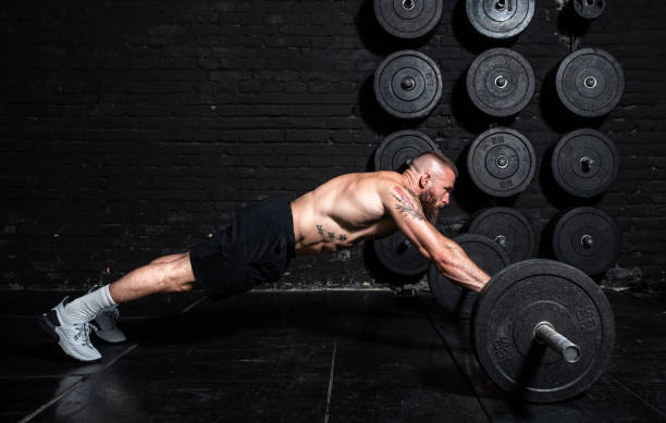 istock Young active strong fit sweaty muscular man with big muscles doing abs workout by rolling barbell weights in the floor of the gym as hardcore cross training real people exercise 1298645826