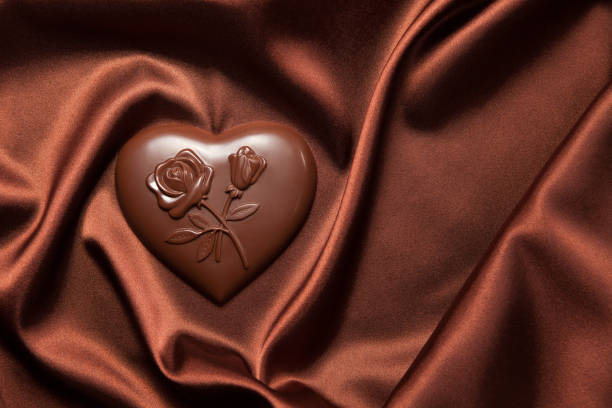 chocolates heart shaped with a pattern of flowers on brown silk. - valentines day candy chocolate candy heart shape imagens e fotografias de stock