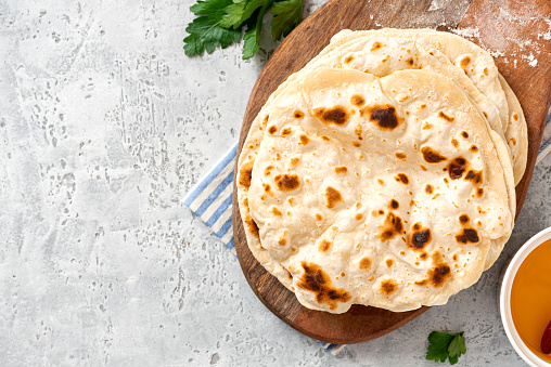 Homemade Roti Chapati Flatbread on gray concrete background top view. Freshly baked indian flatbread. Copy space for text.