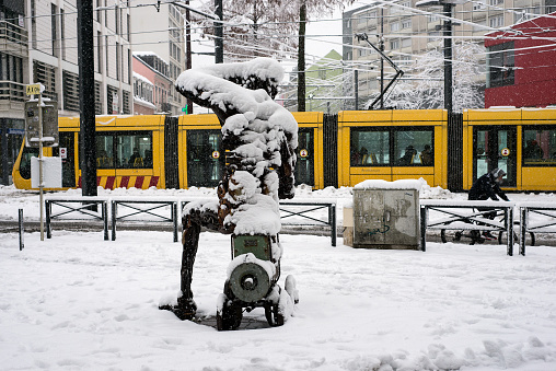 Mulhouse - France 15 January 2021- View of metallic statue and tramway covered by the snow in the street by snowy day