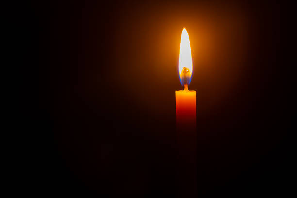 istock Close up single candle light and flame on black background 1298654411