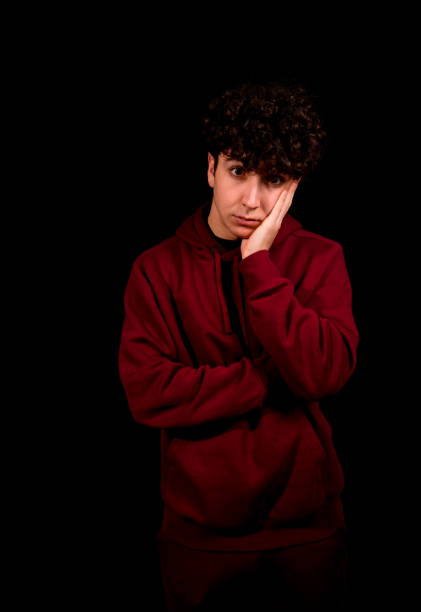 istock Attractive young man with curly hair posing on black background 1298655372