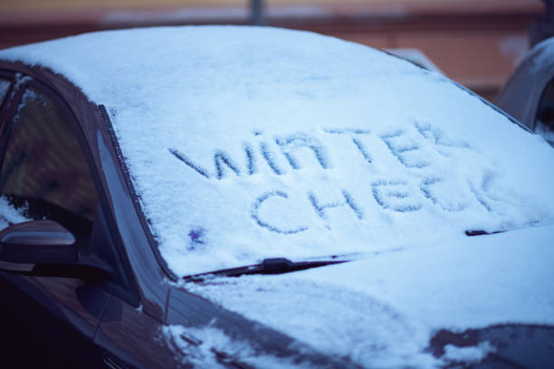 snowy car windshield with winter check inscription outdoors in the city in winter.