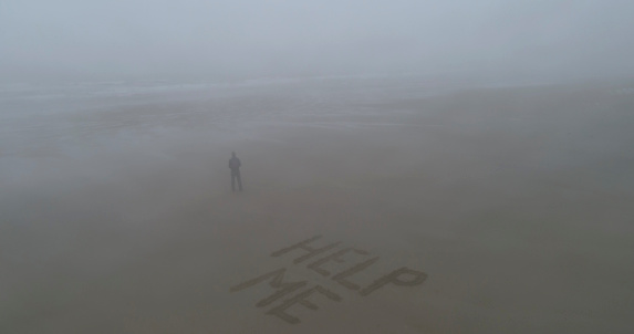 With words 'HELP ME' written in the sand