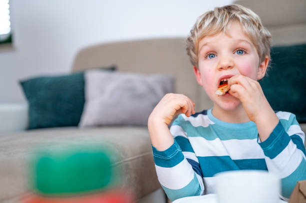 istock Little boy eating pizza at home 1298661280