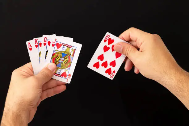 Male hands holding combination of royal flush poker cards on dark background. Casino, luck and fortune concept
