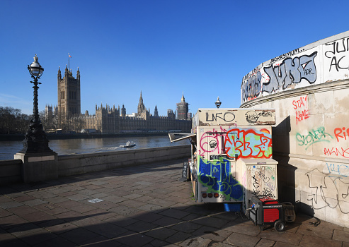 Take away coffee at a food stand covered in graffiti on a corner of the river Embankment overlooking the Houses of Parliament and Westminster, London, UK - 25th January 2021