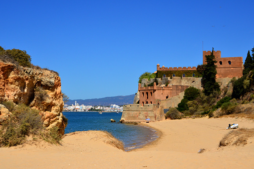 Ferragudo, Algarve / Faro District, Portugal: Praia Grande beach and Fort of São João do Arade, built to protect the Arade river mouth. 17th century fortress by engineer Alexandre Massai with multi-tiered battlements and barbicans.
