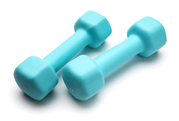 istock Two turquoise colored rubber dumbbells lying at white table 1298669610