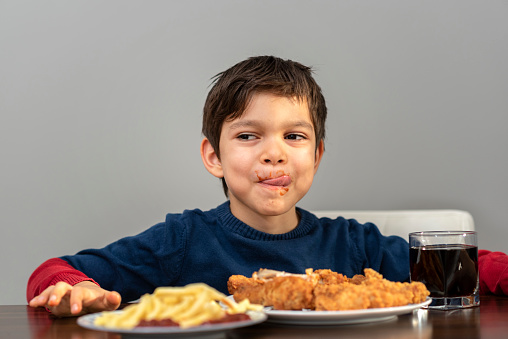 little boy with fried chicken, cola and french fries