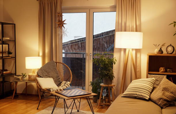 view of a warm light cozy living room in winter with a snowstorm outside - illuminated imagens e fotografias de stock