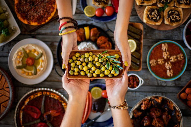 istock Two women’s hands holding green marinated olive fruits in a bowl. 1298672821