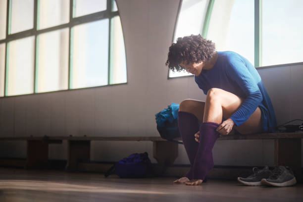 African-american woman with afro hair dressing socks on dance studio African-american woman with afro hair dressing purple socks on dance studio for dance class woman putting on socks stock pictures, royalty-free photos & images