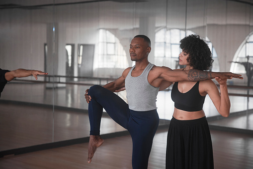 African-american dance instructor teaching student helping with form during dance class in studio