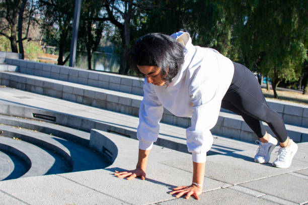 istock Beautiful tan woman doing a push-up in the park. Arm exercise. 1298676248
