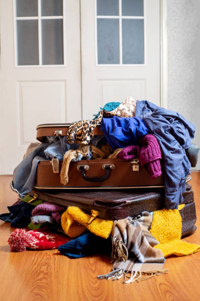 istock Suitcases overflowing with used clothes on the floor. Sorting wardrobe and textiles. Sustainable life 1298678859